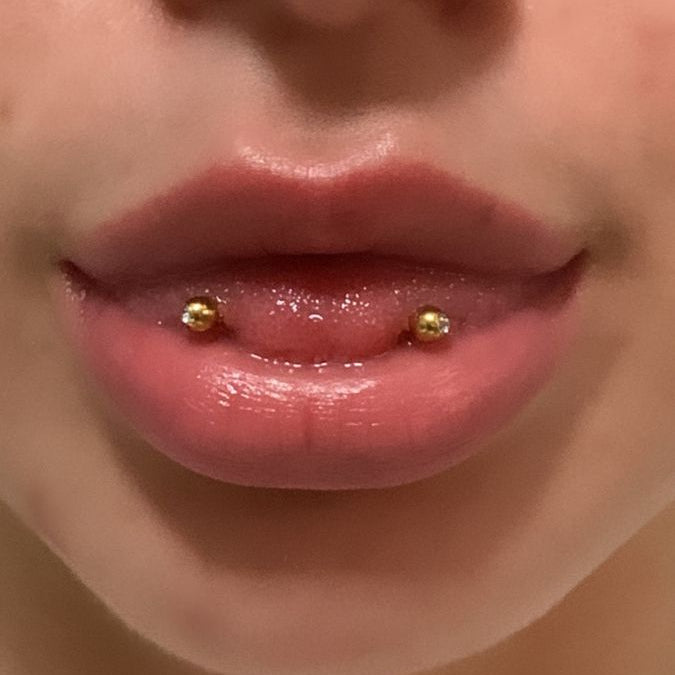 Close-up of a person's lips with gold lip rings.